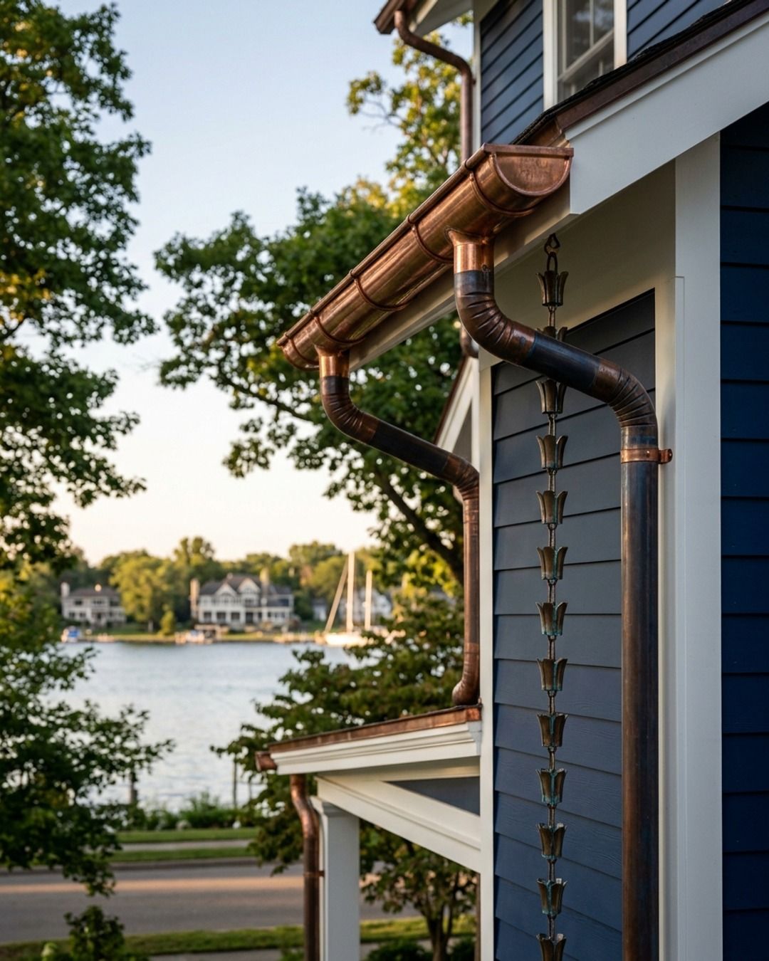 Copper gutters on a blue house with the lake behind it.